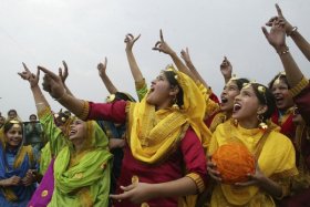 School girls wearing colourful dresses cheer as they fly a kite during an event to mark the Basant or spring festival in Amritsar
